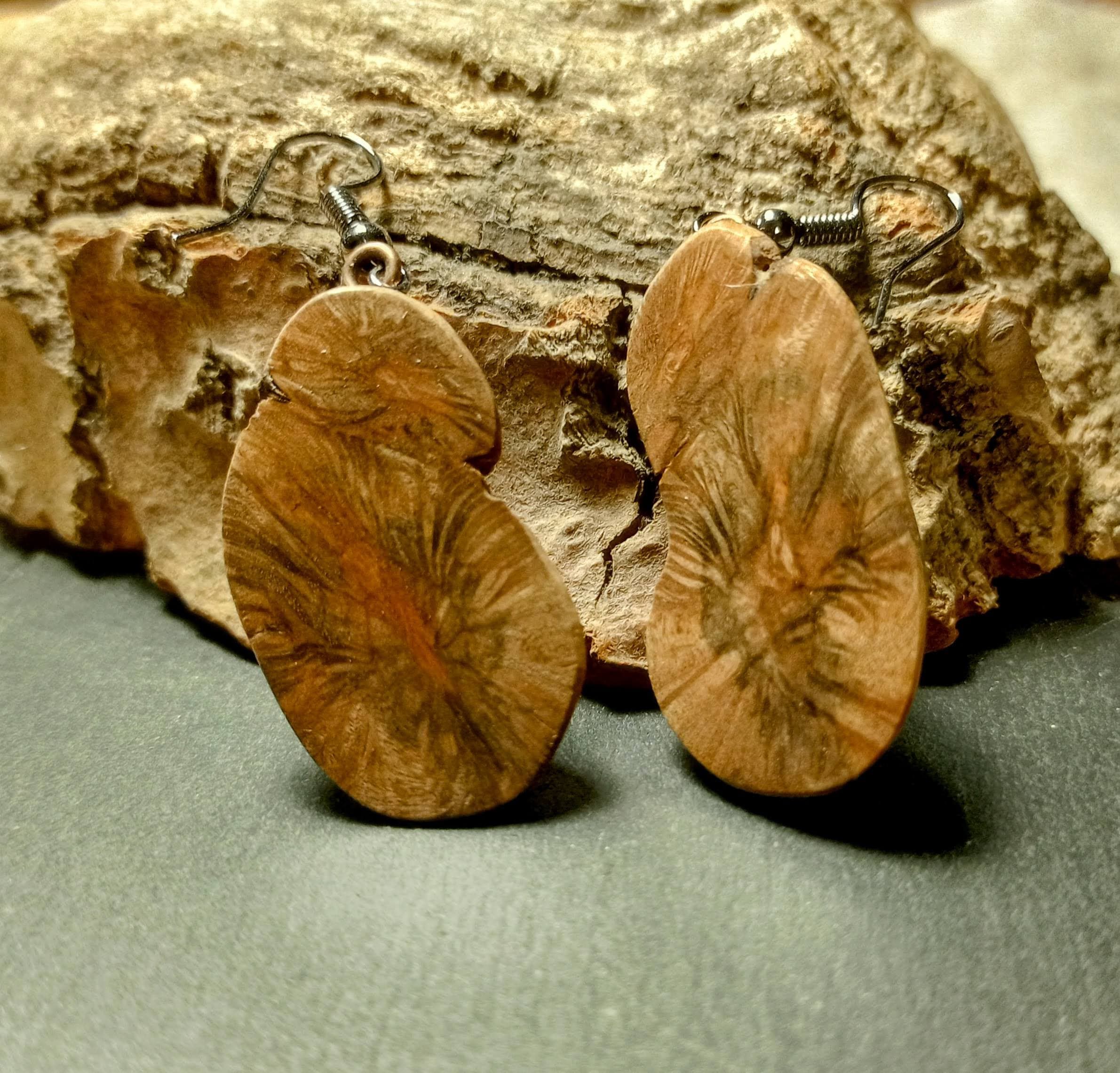 Handgefertigte Ohrhänger aus Weidenperlen auf einem Stück Holz